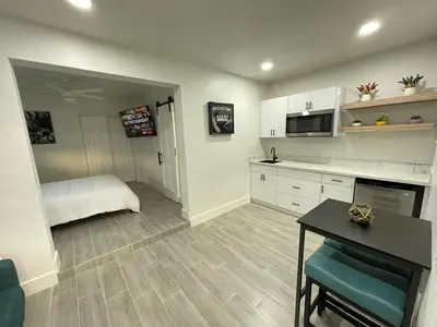 a kitchen with white cabinets and a table and a bed at The Vice City Suite - Private stay with Free Parking in the Heart of Miami in Miami