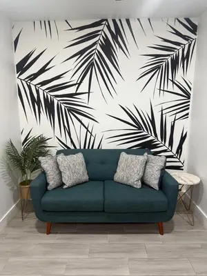 a blue couch in a living room with a palm tree mural at The Vice City Suite - Private stay with Free Parking in the Heart of Miami in Miami