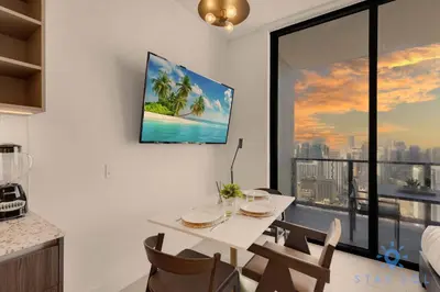 a dining room with a white table and a tv on the wall at Beautiful Studio with Private Balcony Gym & Pool in Miami