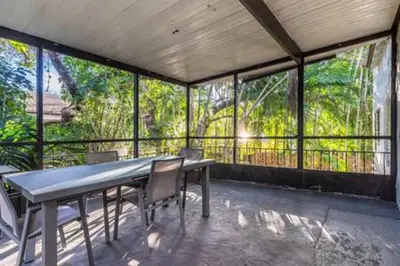 a table and chairs in a room with windows at 1720 Wa Kee 2A · Luxurious 4BR 3BA Retreat in Coconut Grove w Pool in Miami