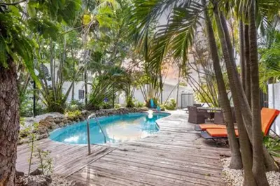 a swimming pool with palm trees and a wooden deck at 1720 Wa Kee 1B · 4 Queen Beds Sleep 8 Pool Parking Wi-Fi Patio in Miami