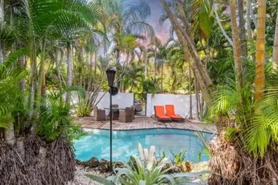 a swimming pool with two chairs and palm trees at 1720 Wa Kee 1B · 4 Queen Beds Sleep 8 Pool Parking Wi-Fi Patio in Miami
