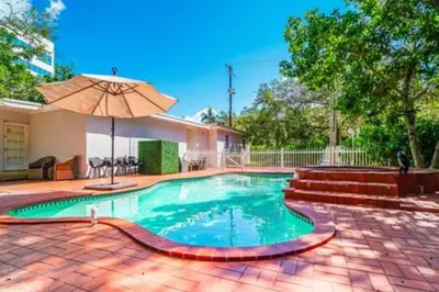 a swimming pool with an umbrella in a yard at 2710 · Heated Pool 7 Beds 5 Baths Sleep 15 Park 4 Car in Miami