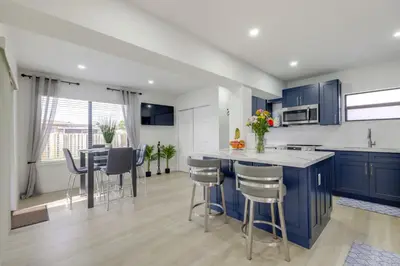 a kitchen with blue cabinets and a table with stools at 3 Mi to Hard Rock Stadium Retreat with Private Yard in Miramar