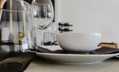 a white bowl on a plate on a table with glasses at KOOSH - Boutique Aparthotel in Fort Lauderdale