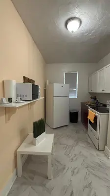 a small kitchen with a white refrigerator and a table at The Studio 6 Little Havana Walk to Marlins Stadium in Miami