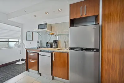 a kitchen with a stainless steel refrigerator and wooden cabinets at Ocean Drive Apt with Balcony & Rooftop Pool in Miami Beach