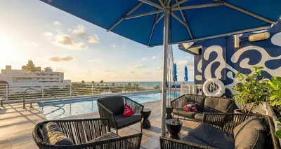 a balcony with two chairs and an umbrella on a cruise ship at Ocean Drive Apt with Balcony & Rooftop Pool in Miami Beach