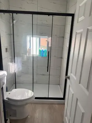 a bathroom with a glass shower with a toilet at Charming Historic Home with Modern Comforts in Opa-locka