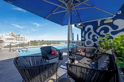 a patio with chairs and an umbrella and a pool at Spacious APT on South Beach Roof Top Pool & Bar in Miami Beach