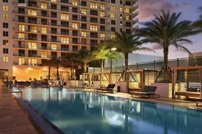 a swimming pool with palm trees and a building at Luxury Corner Apartment in Hollywood Beach in Hollywood