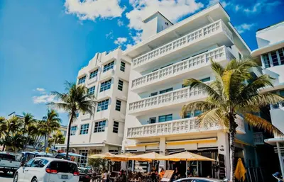 a white building with palm trees in front of it at Heart of South Beach Studio Roof Top Pool Balcony in Miami Beach