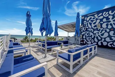 a patio with blue chairs and umbrellas on the beach at Heart of Ocean Drive - Studio - Rooftop Pool in Miami Beach