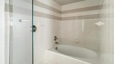 a white bathroom with a tub and a shower at Landing Apartments - Fort Lauderdale in Fort Lauderdale
