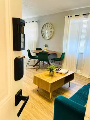 a living room with a table and chairs and a clock at Balcony 2BR Apartment with Free Parking near Freedom Park & Brickell in Miami