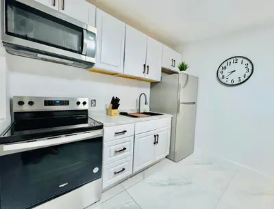 a kitchen with white cabinets and a stainless steel refrigerator at Earth-Toned Escape, Stylish Stay in Miami