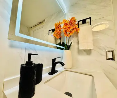 a bathroom with a sink and a vase of orange flowers at Earth-Toned Escape, Stylish Stay in Miami