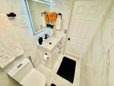 a white bathroom with a toilet and a sink at Earth-Toned Escape, Stylish Stay in Miami