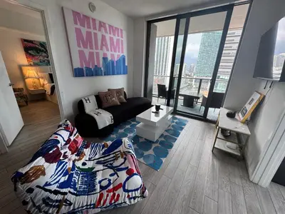 a living room with a couch and a room with a large window at Spectacular corner 2BDR Downtown Miami in Miami
