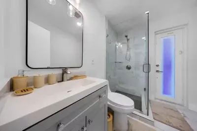 a bathroom with a sink and a toilet and a mirror at Hidden Miami Oasis Heated Pool and Games in Golden Glades
