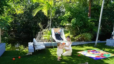 a woman and a child playing in the grass at Hidden Miami Oasis Heated Pool and Games in Golden Glades