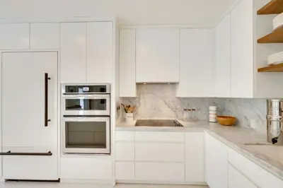 a white kitchen with white cabinets and appliances at Biscayne Park Urban Oasis with Lush Backyard! in Biscayne Park