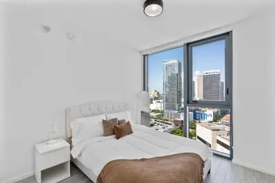a bedroom with a white bed and a large window at Downtown Miami Luxe Studio Suite in Miami