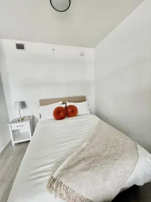 a white bed with two orange pillows on it at Downtown Miami Luxe Studio Suite in Miami