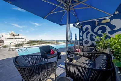 a patio with chairs and an umbrella and a pool at Spacious Studio with Roof Top Pool & Bar in Miami Beach