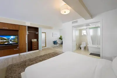 a bedroom with a bed and a tv and a bathroom at Spacious Studio - Roof Top Pool & Bar South Beach in Miami Beach