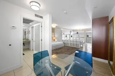 a living room with a glass table and a bedroom at Spacious Studio - Roof Top Pool & Bar South Beach in Miami Beach