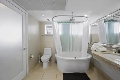 a white bathroom with a toilet and a sink at Spacious Studio - Roof Top Pool & Bar South Beach in Miami Beach
