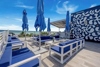 a deck with blue chairs and umbrellas on the beach at Ocean Drive Studio with Rooftop Pool Prime Location in Miami Beach