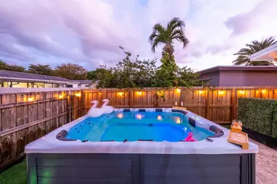 a hot tub in a backyard with a fence at NEW Hollywood Luxury Villa, Game Room, Hot Tub 12, Fire Pit & BBQ in Hollywood