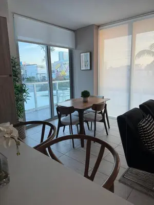 a dining room with a table and chairs in a living room at Stylish 2BR Quadro Luxe Stay in Design District in Miami