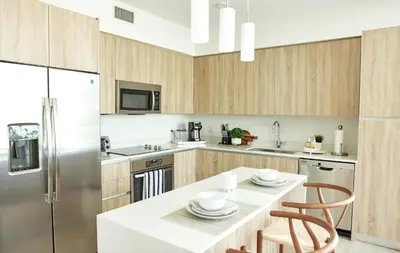 a kitchen with a white counter top and wooden cabinets at Stylish 2BR Quadro Luxe Stay in Design District in Miami