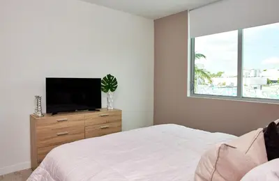 a bedroom with a bed and a tv on a dresser at Stylish 2BR Quadro Luxe Stay in Design District in Miami