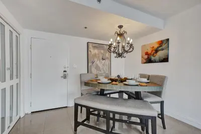 a dining room with a table with chairs and a chandelier at Modern Beach Retreat 2BR and 2BA Pools, Sauna, Gym Oceanfront Building 1615 in Miami Beach