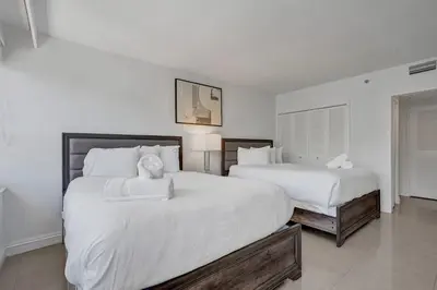 two beds in a bedroom with white walls at Modern Beach Retreat 2BR and 2BA Pools, Sauna, Gym Oceanfront Building 1615 in Miami Beach