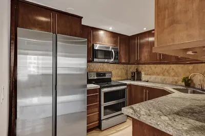 a kitchen with wooden cabinets and a stainless steel refrigerator at Modern Beach Retreat 2BR and 2BA Pools, Sauna, Gym Oceanfront Building 1615 in Miami Beach