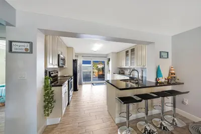 a kitchen with white cabinets and black counter tops at Waterfront Retreat Home Dania Beach in Dania Beach