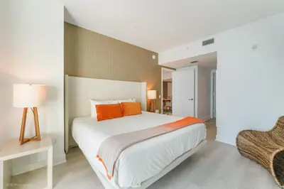 a bedroom with a large white bed with orange pillows at LYFE Resort Ocean View Penthouse in Hollywood