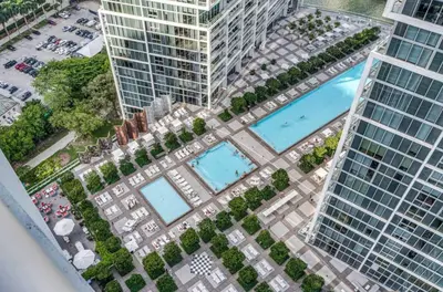 an overhead view of a pool in a city with tall buildings at W hotel High end ocean view 2 bedroom at icon brickell in Miami