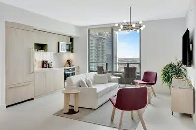 a living room with a white couch and a kitchen at 40th floor lux condo with pool, gym and spa access in Miami