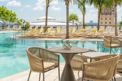 a patio with tables and chairs next to a swimming pool at 40th floor lux condo with pool, gym and spa access in Miami