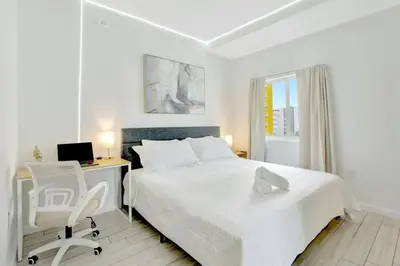 a white bedroom with a bed and a desk and a computer at Chic 2BR Edgewater Condo with Views plus Balcony in Miami