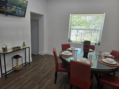 a dining room with a table and chairs and a television at Little Wynwood Oasis in Miami