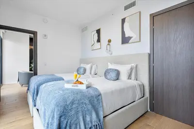 a hotel room with two beds with blue sheets at Top-floor 3BR Stay with skyline views in Miami