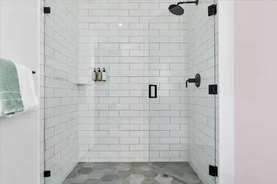 a bathroom with a shower with white tiles at Top-floor 3BR Stay with skyline views in Miami