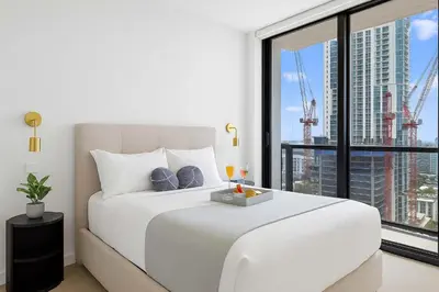 a bedroom with a white bed with a large window at Top-floor 3BR Stay with skyline views in Miami